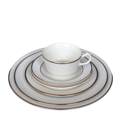 A stack of plates rimmed with metallic gold rings. A coffee cup with a similar pattern sits on top.