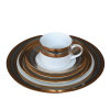 A stack of plates rimmed with metallic gold and silver rings. A coffee cup with a similar pattern sits on top.