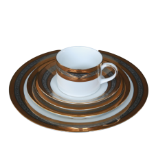 A stack of plates rimmed with metallic gold and silver rings. A coffee cup with a similar pattern sits on top.