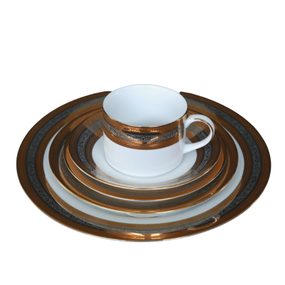 A stack of plates rimmed with metallic gold and silver rings. A coffee cup with a similar pattern sits on top.
