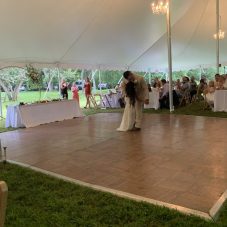 A photo of a parquet dance floor, with wooden tiles laid in opposing patterns. A bride and groom are dancing on it.