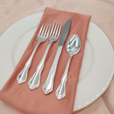 Croyden Silver flatware on a place setting with a coral napkin, white plate, and peach tablecloth.