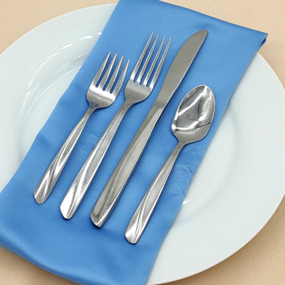 Trivoli Stainless Flatware on a place setting with a blue napkin, white plate, and yellow tablecloth.