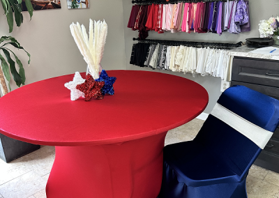red spandex linens on a 36 inch pedestal table at a seated height, with a folding chair covered with a royal blue spandex chair cover.