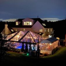Clear tent at night showing rental tent lighting, and table and chair rentals for a party.